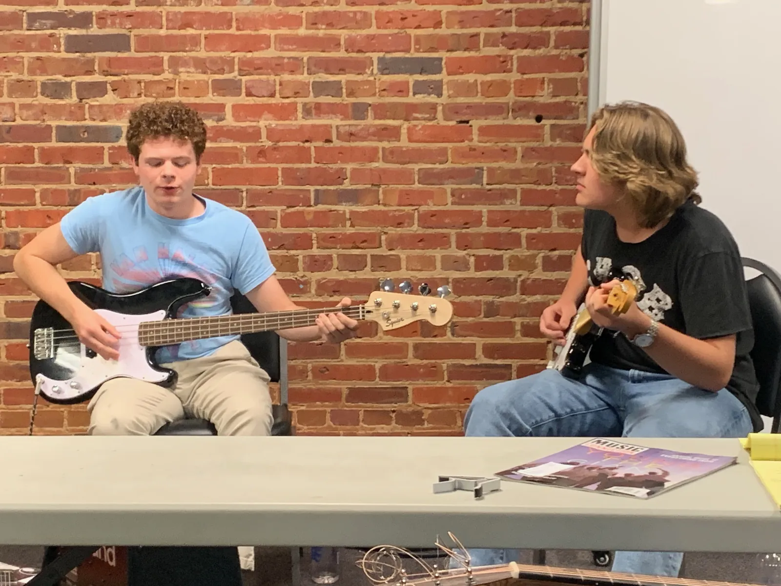 Two seated attendees play the guitar